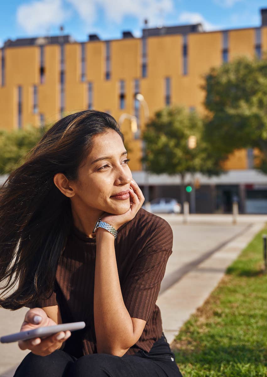 woman outside sitting and looking around the park